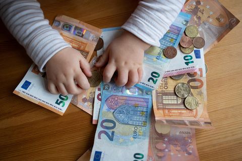 Kindergeldantrag: Baby spielt mit Geld