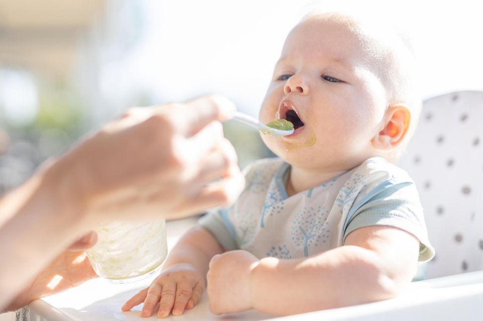 Vegetarische Babyernährung: Ein Baby öffnet den Mund für einen Löffel mit Brei