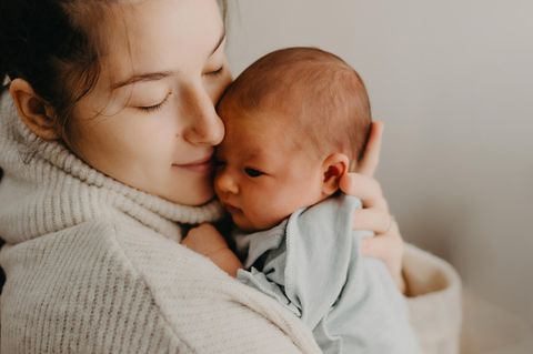 Herpes bei Babys: Frau hält und kuschelt ein neugeborenes Baby