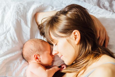 Ambulante Geburt: Frau und Neugeborenes liegen schlafend im Bett