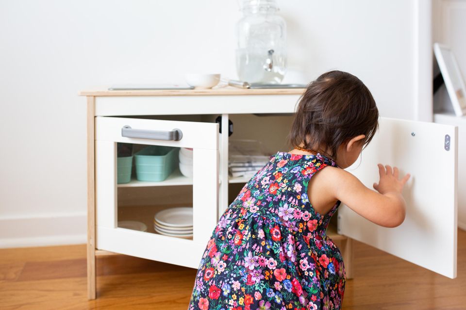 Montessori in der Küche: Kind öffnet Schrank einer Spielküche