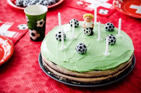 Fußball-Geburtstag: Ein Kuchen in Fußball-Optik, mit grünem Topping sowie Fußbällen und einem Fußballer als Dekoelement