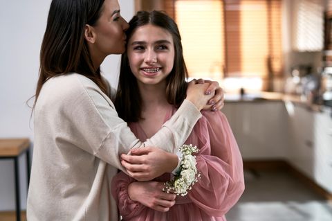 Geschenke zur Konfirmation: Mutter küsst ihre Tochter vor der Konfirmation