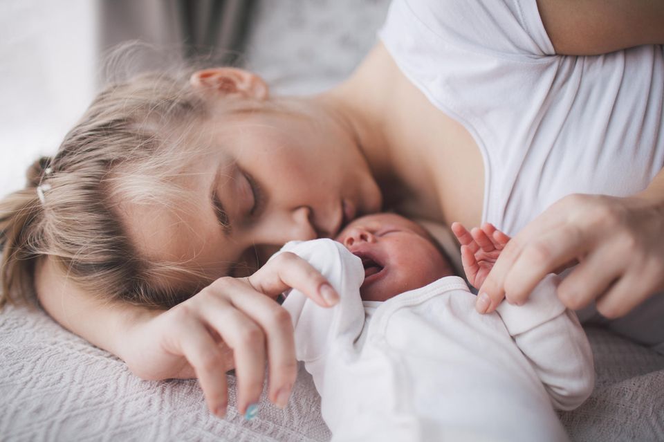 Wochenfluss nach Kaiserschnitt: Frau kuschelt mit einem Neugeborenen
