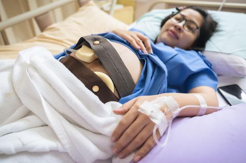 Wehentropf: Schwangere liegt mit CTG und Infusion im Bett