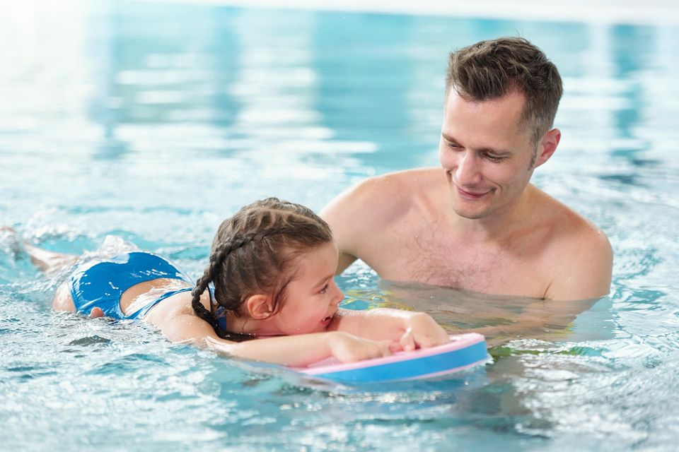 Schwimmen lernen mit Kindern: Vater übt schwimmen mit seiner Tochter