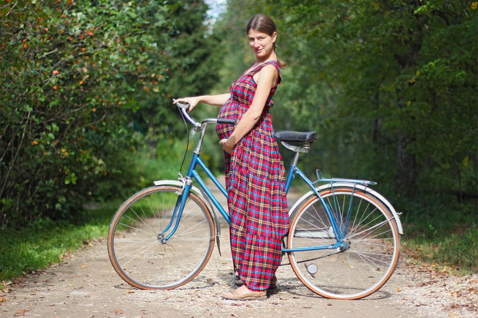 Fahrradfahren in der Schwangerschaft: Schwangere steht vor einem Fahrrad