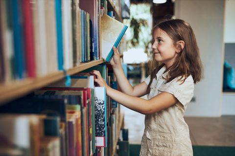 Weltbuchtag: Mädchen zieht ein Buch aus dem Buchregal.