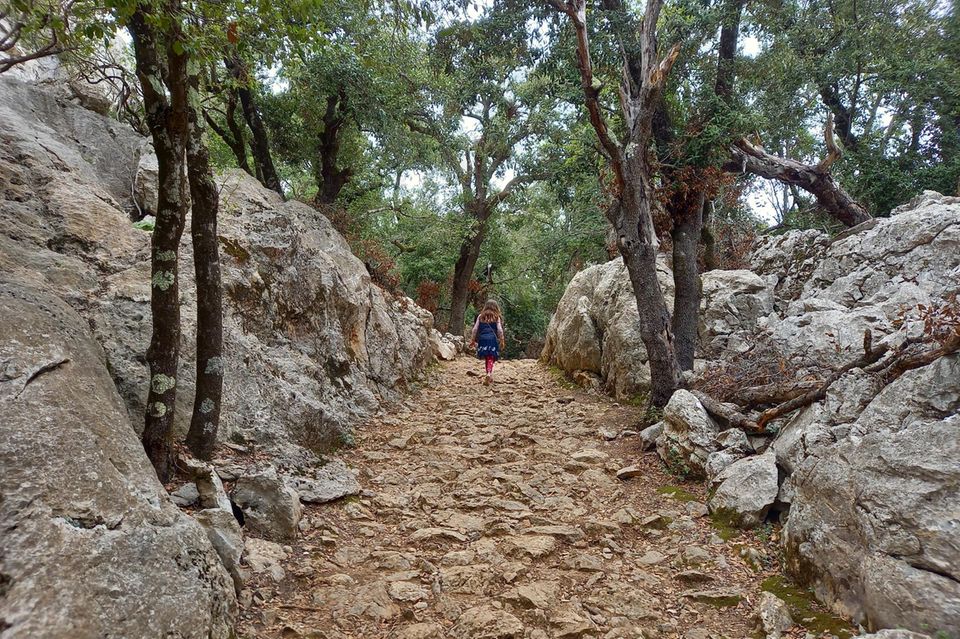 Mallorca mit Kindern: Mädchen auf einem steinigen Waldwanderweg.