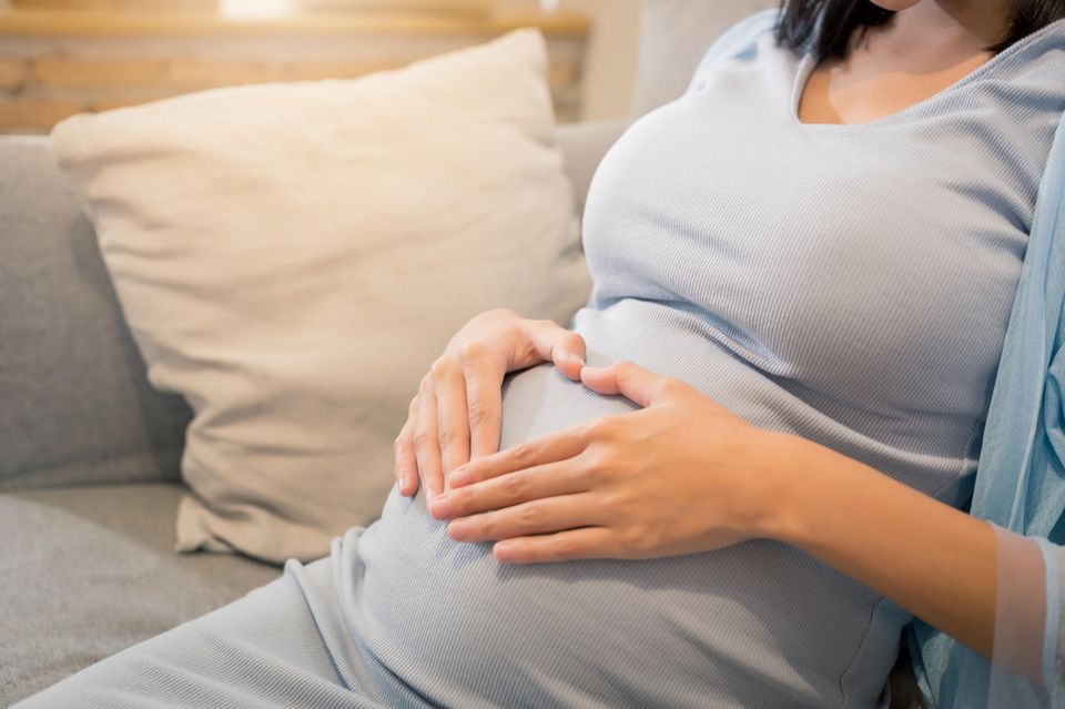 Zervixinsuffizienz: Schwangere formt ihre Hände auf dem Bauch zu einem Herz