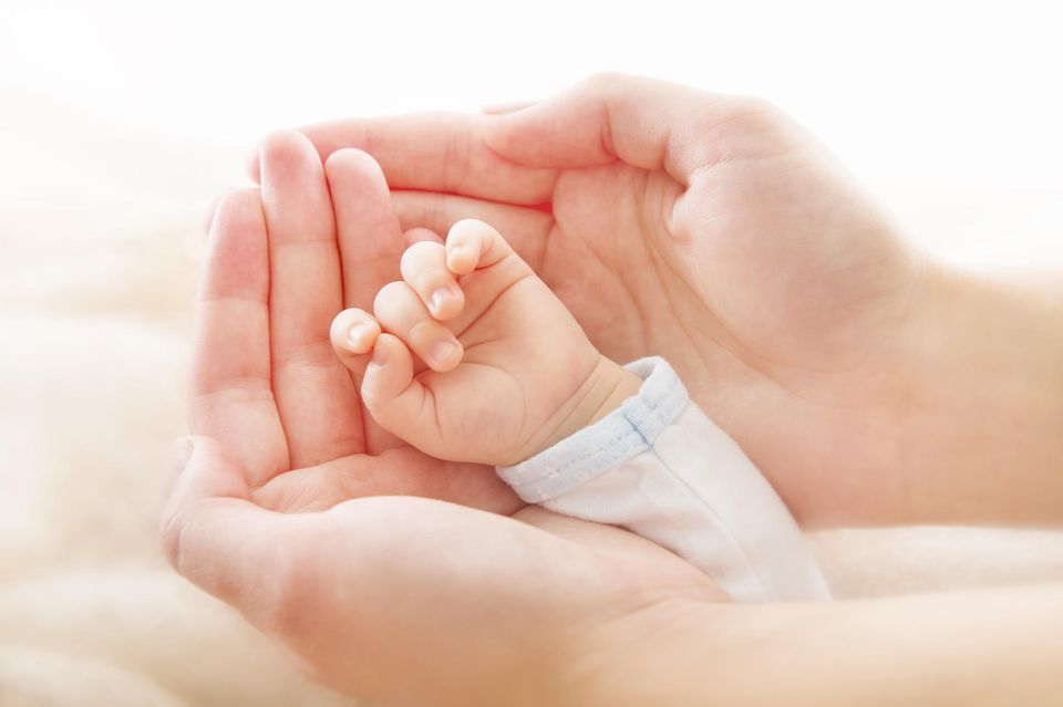 Vierfingerfurche: Hand eines Babys liegt in den Händen einer erwachsenen Person