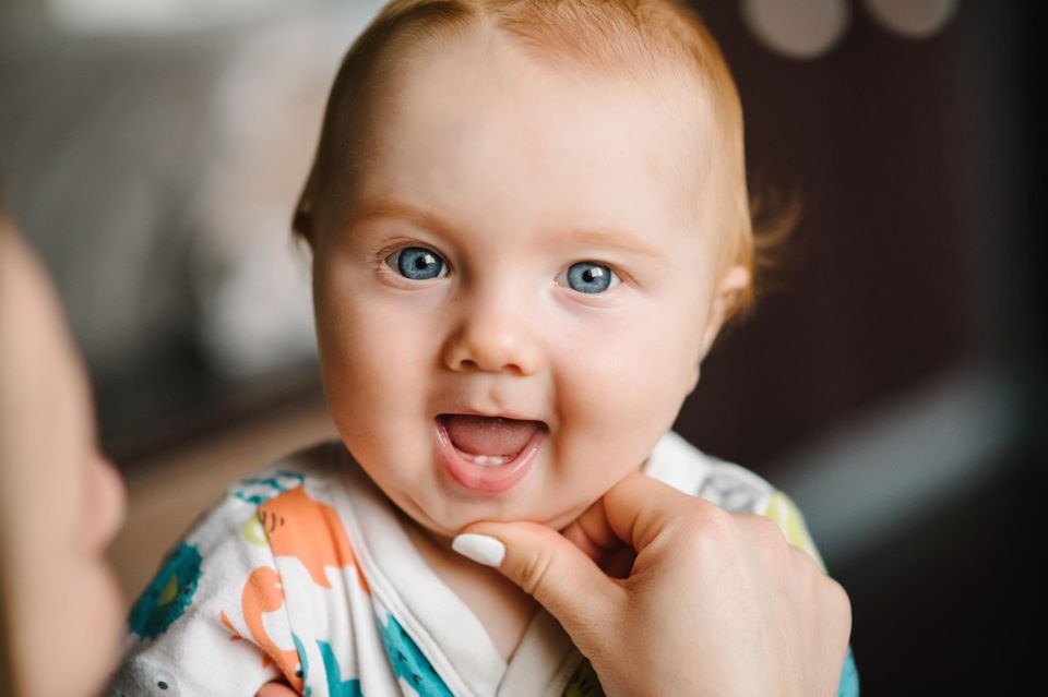 Ab wann zahnen Babys? Baby mit zwei Zähnen lacht in die Kamera