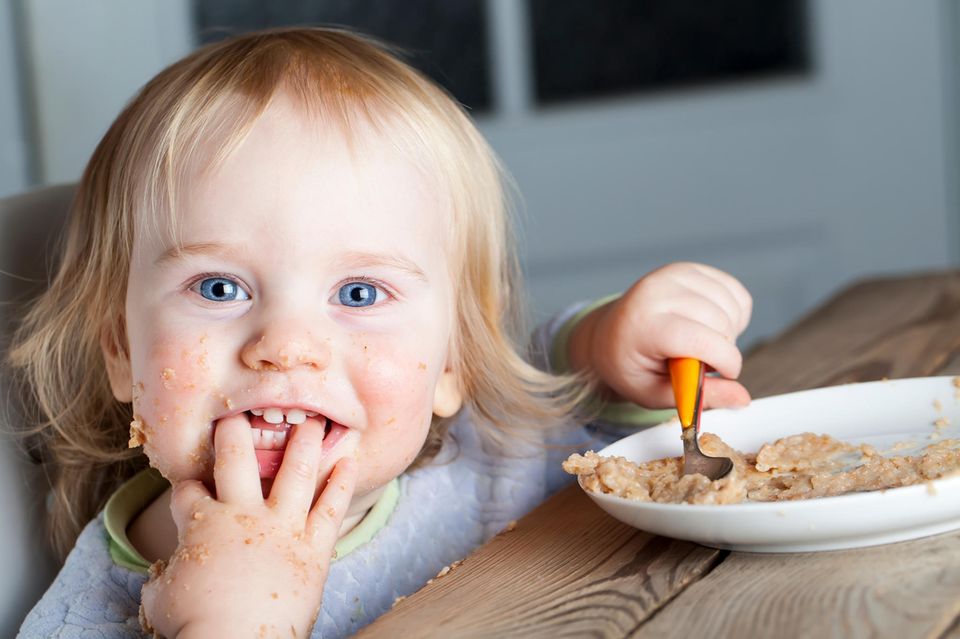 Haferflocken für Babys: Ein Baby isst einen Teller mit Porridge