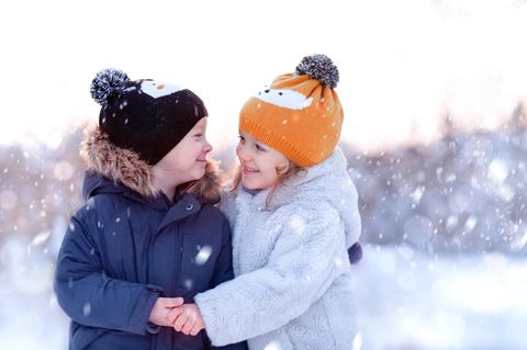 Geschwister umarmen sich im Schnee