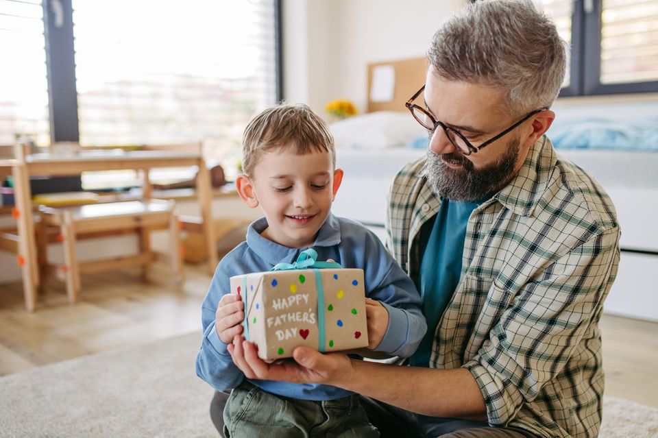 Vatertagsgeschenk basteln: Kind übergibt Geschenk an Vater