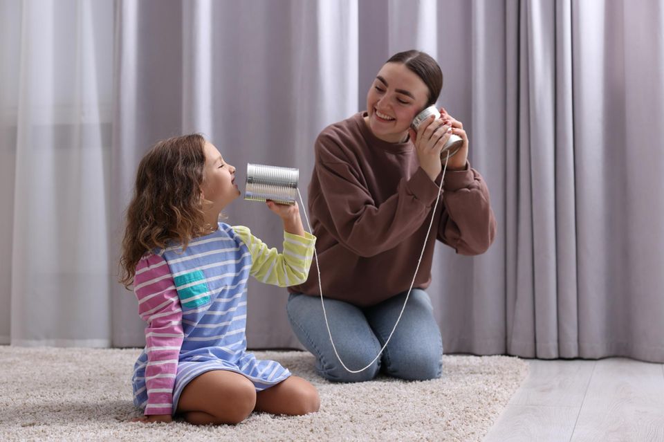 Mama und Kind mit einem Dosen-Telefon