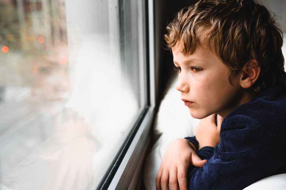 Einsame Kinder: Trauriger Junge sitzt am Fenster