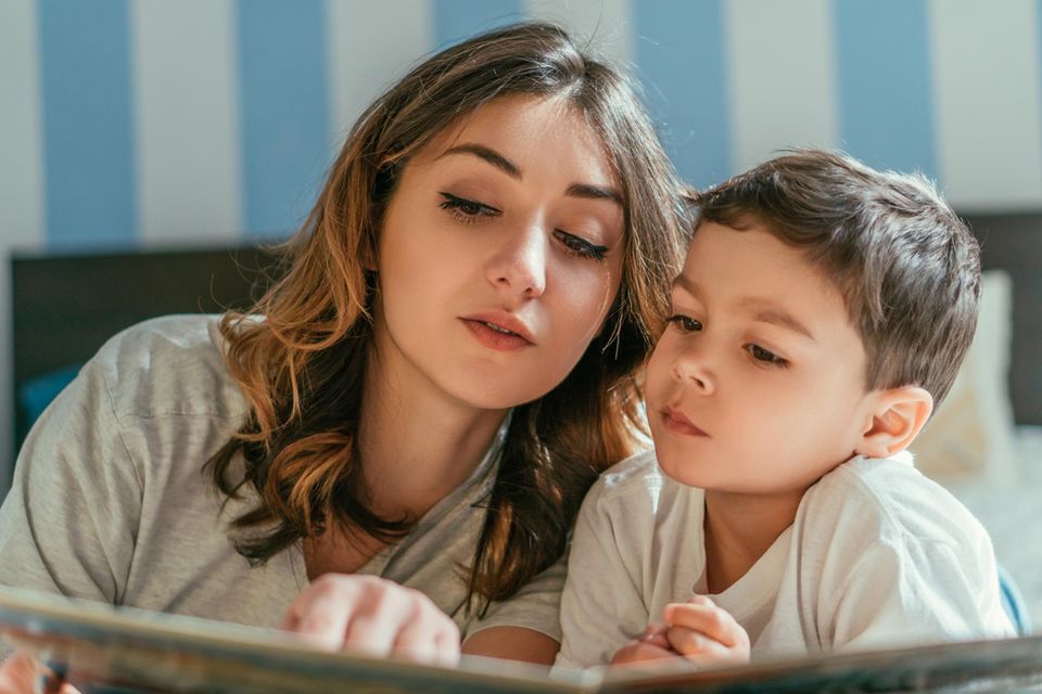 Frau liest Jungem aus einem Buch vor